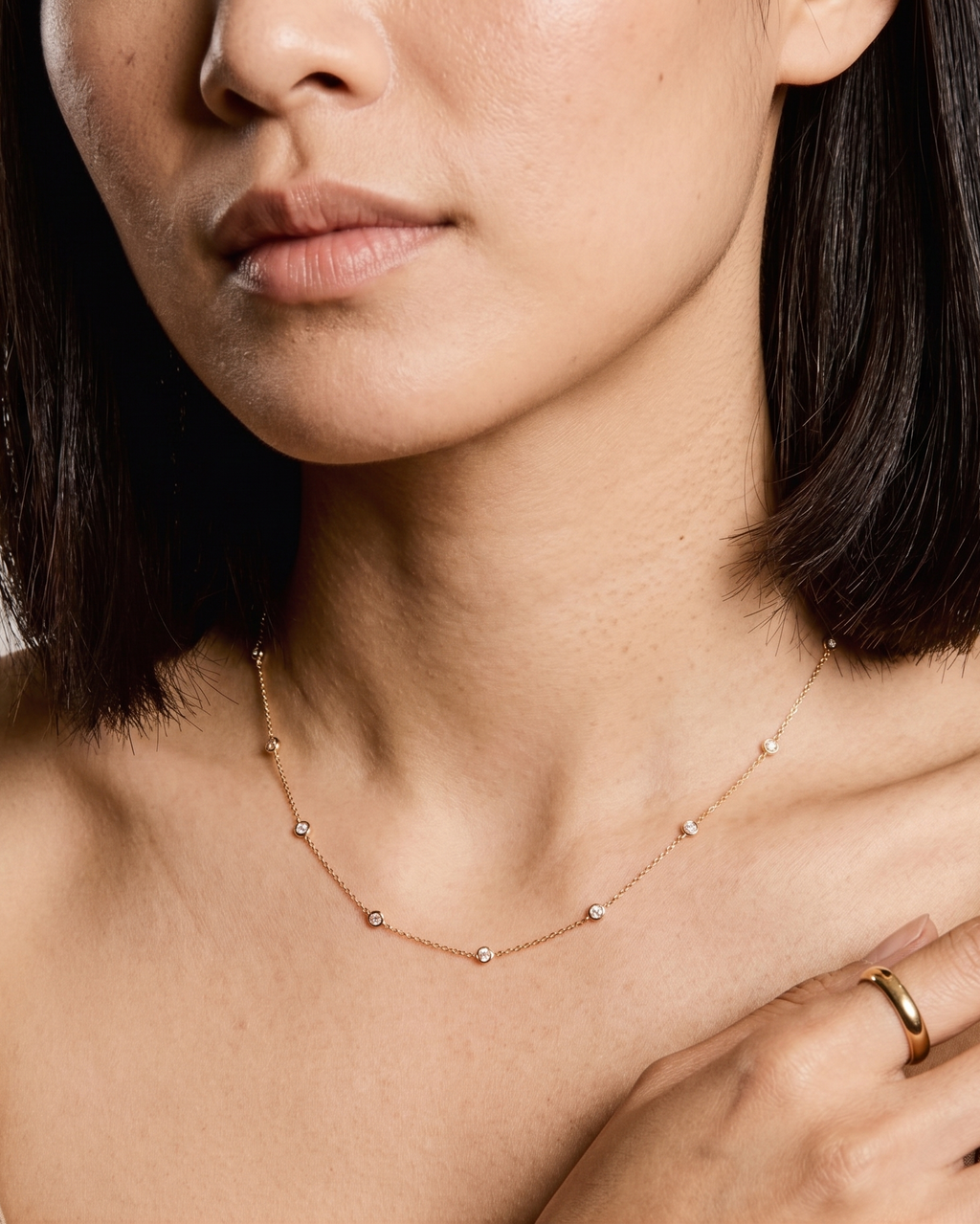 Close-up of a woman wearing a delicate gold necklace and ring.