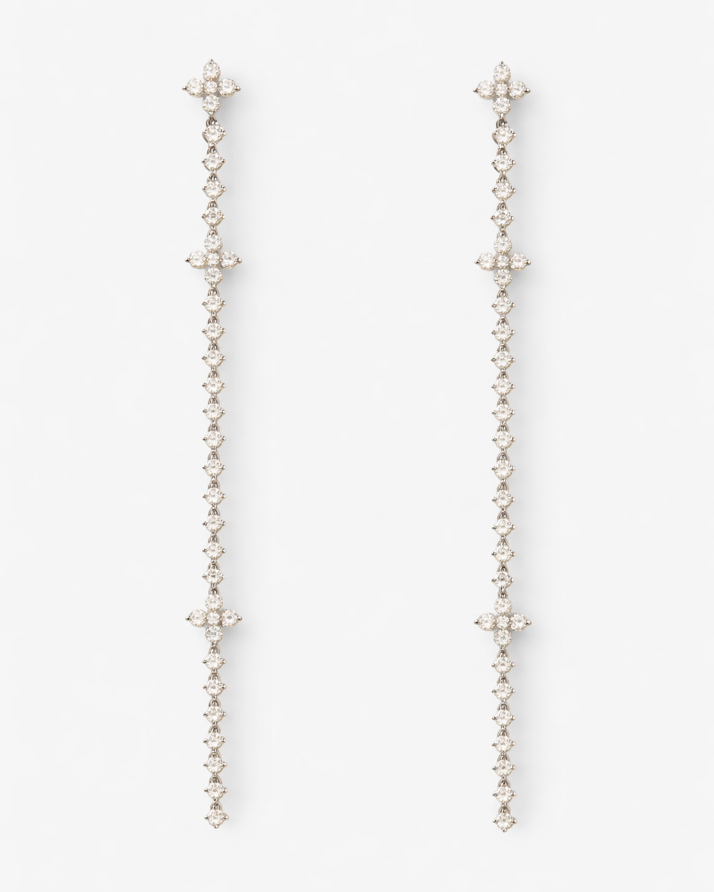 Pair of long, thin earrings with star-like ends on a white background