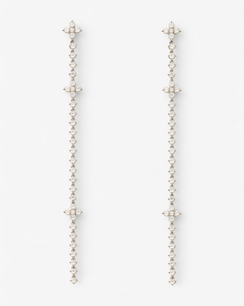 Pair of long, thin earrings with star-like ends on a white background