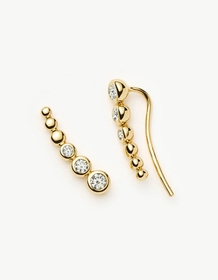 Gold earrings with clear gemstones on a white background
