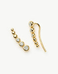 Gold earrings with clear gemstones on a white background