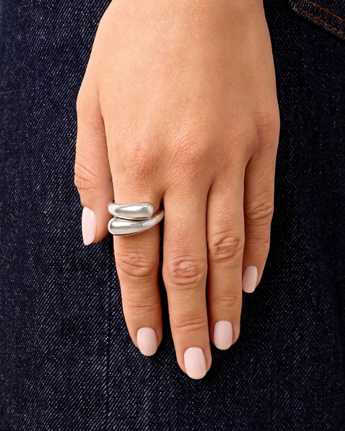 Hand wearing a silver ring on a dark denim background