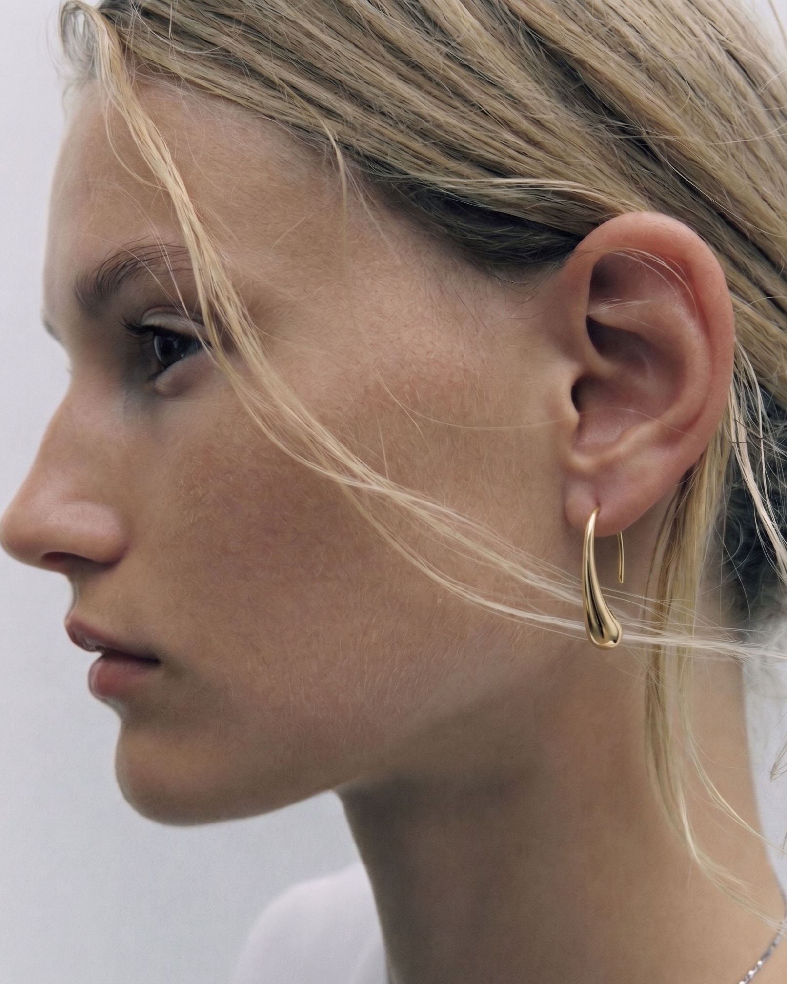 Close-up of a woman wearing a gold hoop earring with a blurred background