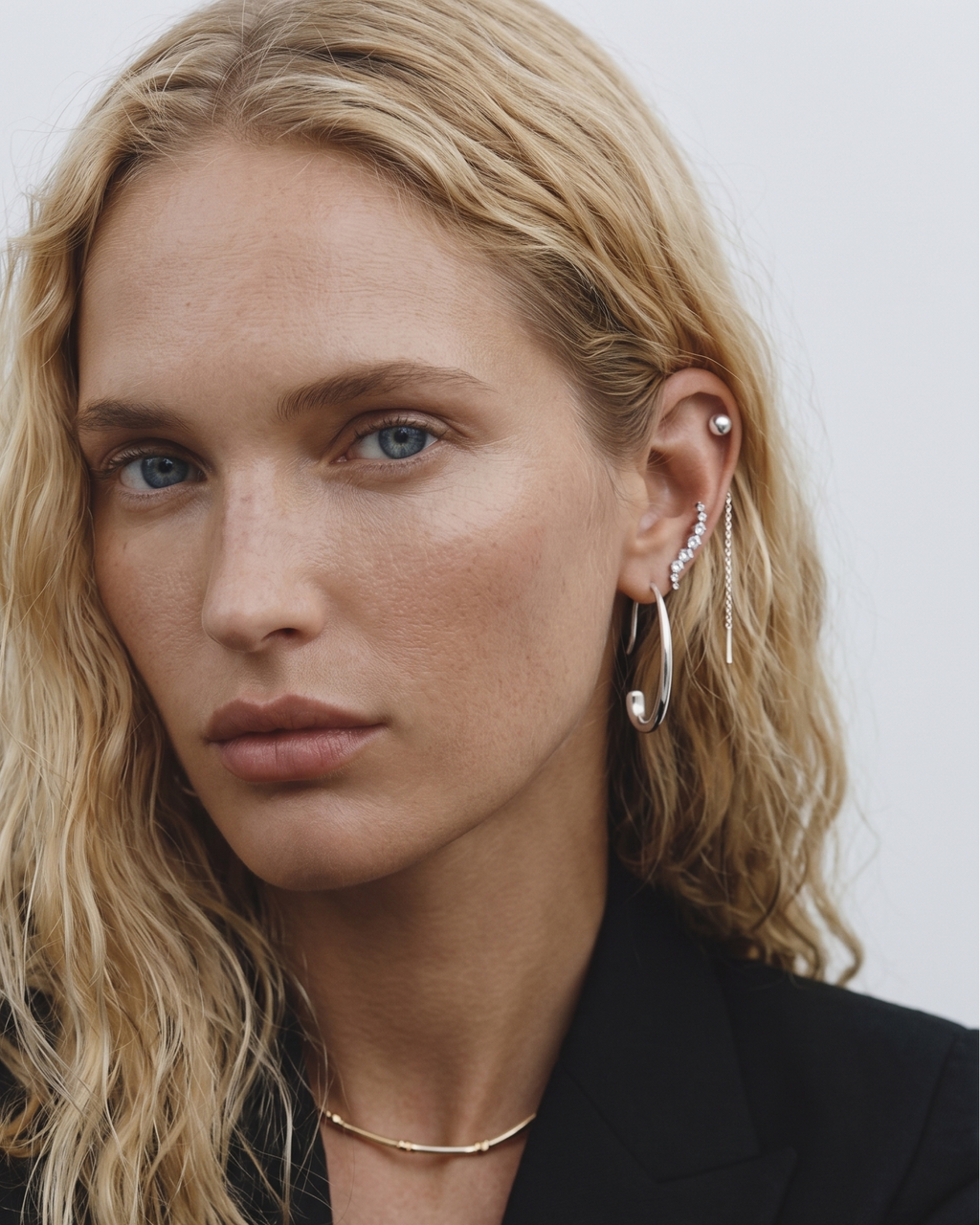 Woman wearing gold jewelry against a neutral background