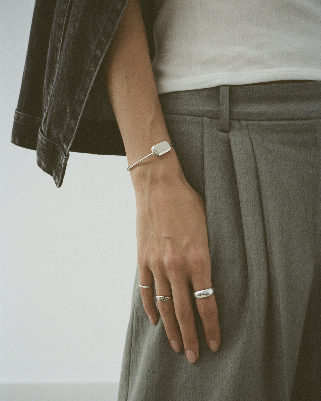 Person wearing multiple rings on a plain background