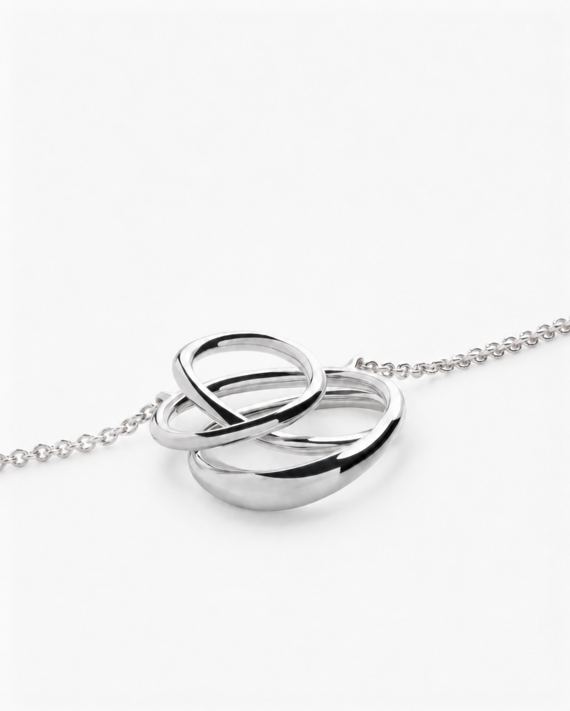 Silver interlocking ring necklace on a white background
