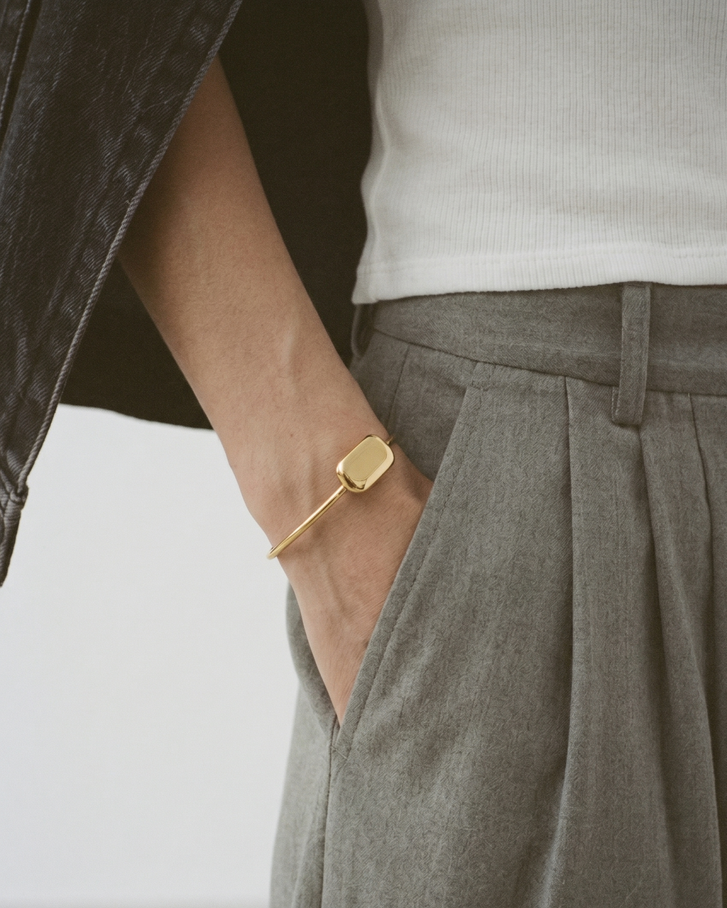 Person wearing a gold bracelet with a plain background