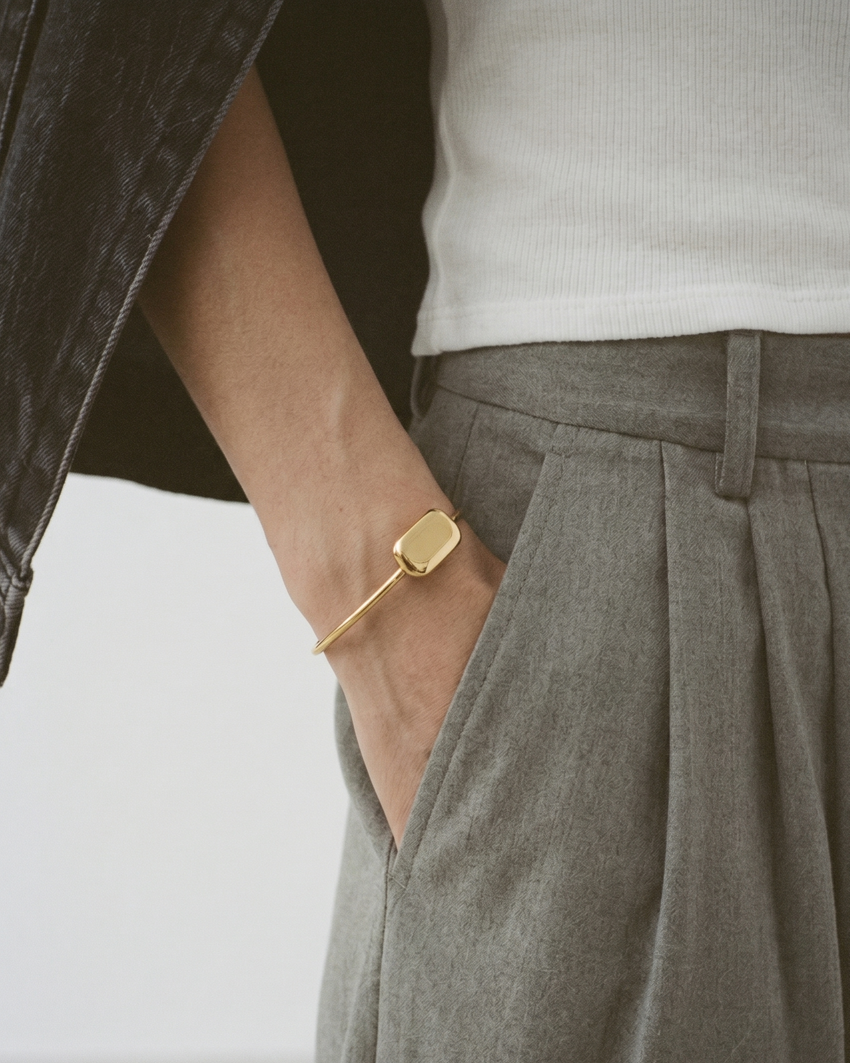 Person wearing a gold bracelet with a plain background
