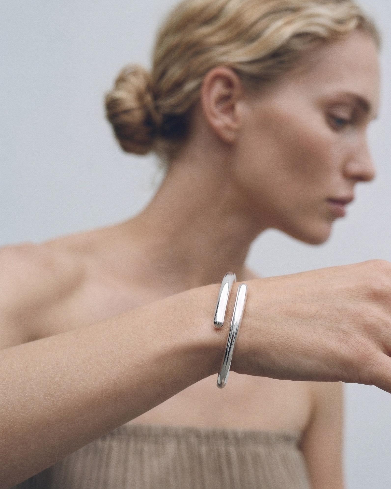 Woman wearing a silver bracelet on a plain background