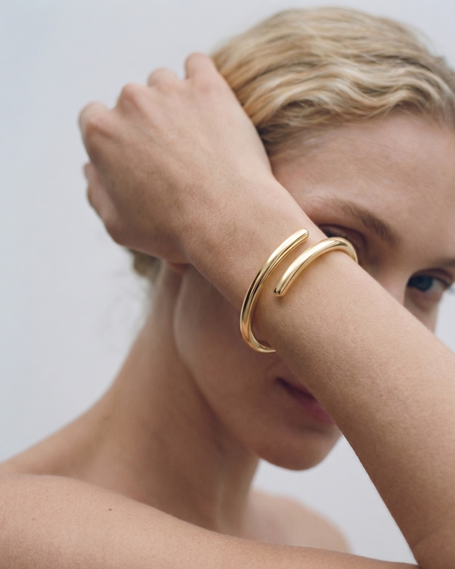 Woman wearing a gold bracelet on a plain background