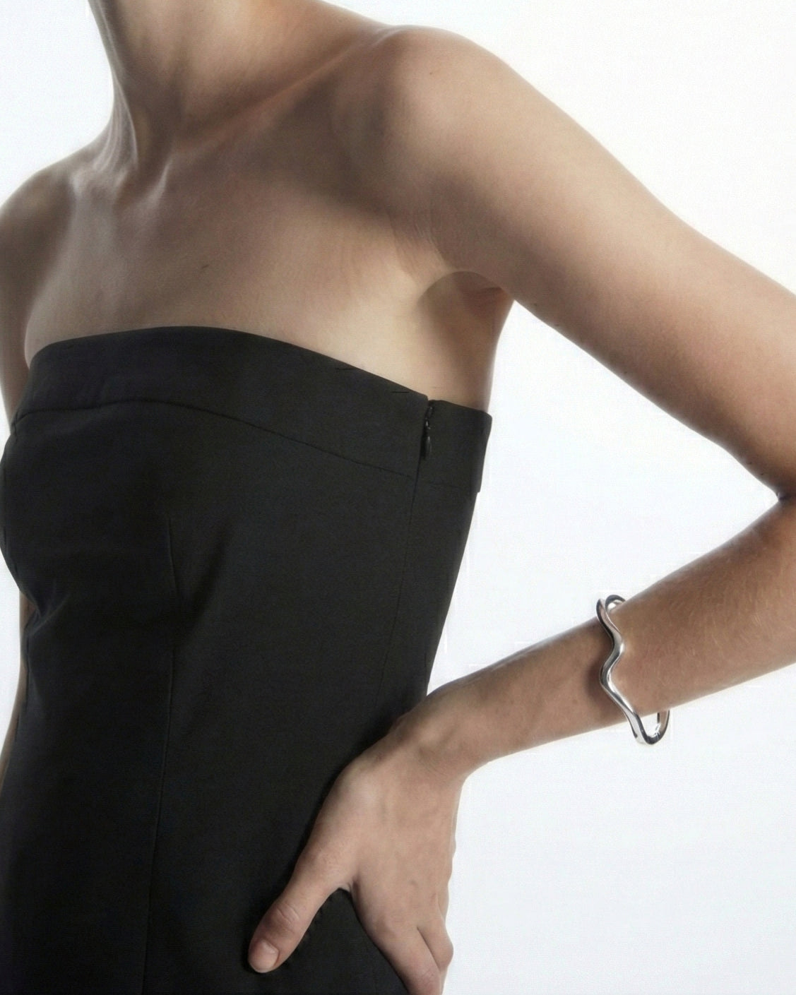 Person wearing a strapless black dress on a white background